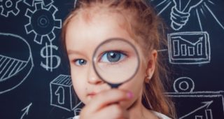 Little girl looking through a magnifying glass on dark background with pattern. close-up